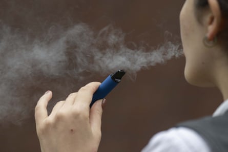 A female breathes retired a unreality of vapur from a vape device