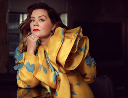 Melissa McCarthy in a yellow-gold silk dress robe with blue leaves and multi-layered neckline