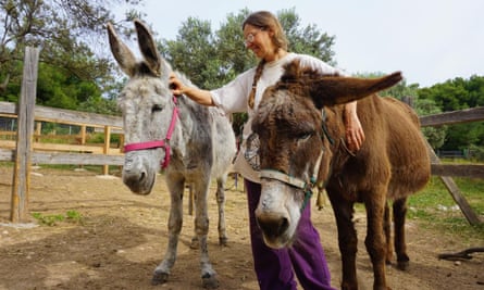 Alexia Papagiannakos Anni stands between two donkeys with her hands on their heads