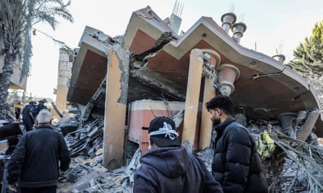 Palestinians look at a destroyed building