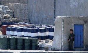 A North Korean soldier stands guard near oil barrels in the North Korean town of Sinuiju, by the Chinese border