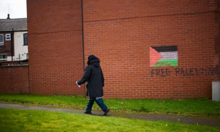 A person walks past a ‘free Palestine’ mural on a wall