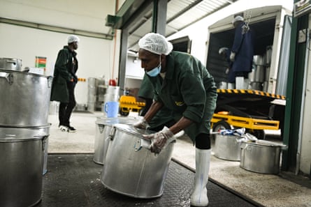 A worker picks up a large catering saucepan.