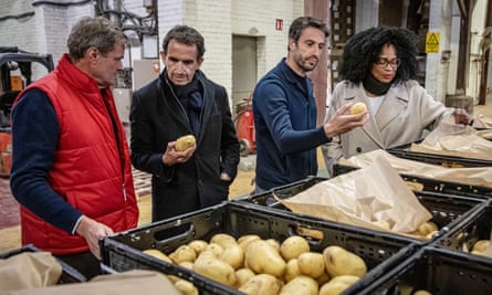 Três homens e uma mulher olham para caixas de batatas em uma fazenda de batatas. 