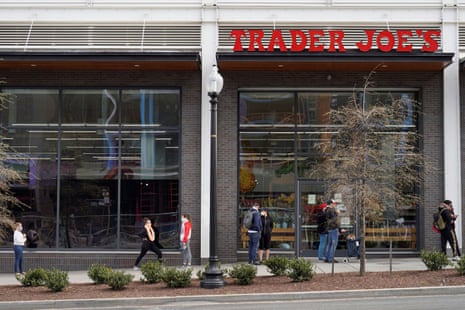 People maintain social distancing as they wait to enter a Trader Joe’s grocery store. 