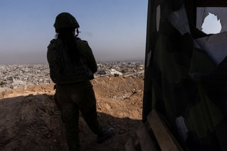 An Israeli soldier is silhouetted against the ruins of Gaza