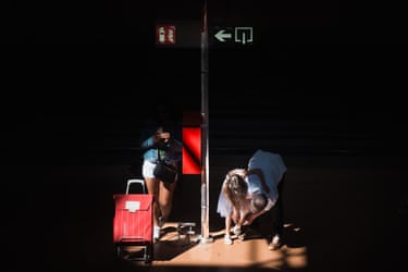 A woman, a man and a young girl are seen in a small circle of light. The main helps the girl put on a sandal