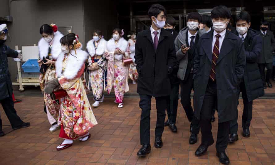 20歳の男女が2021年1月11日に日本の轟のアリーナを離れるとき、着物とスーツを着ています。