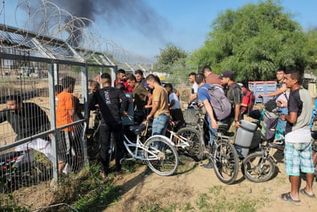 A group of people pass through a hole in a fence
