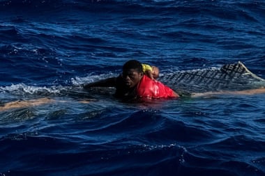 A teenager holds a baby above water after a shipwreck in the Mediterranean Sea