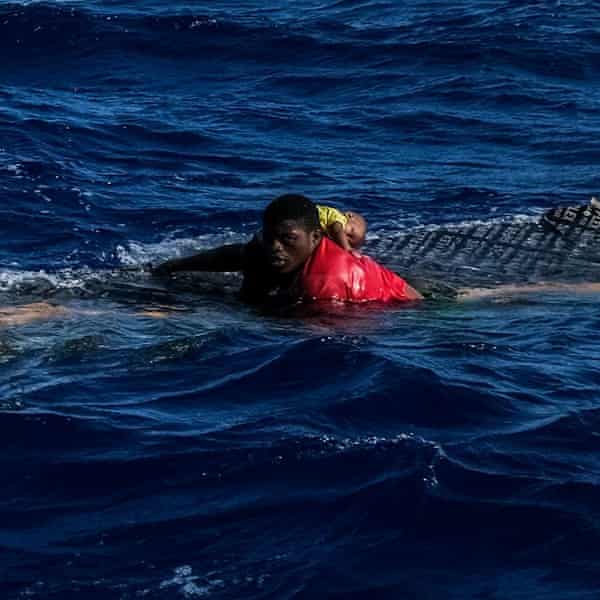 A teenager holds a baby above water after a shipwreck in the Mediterranean Sea
