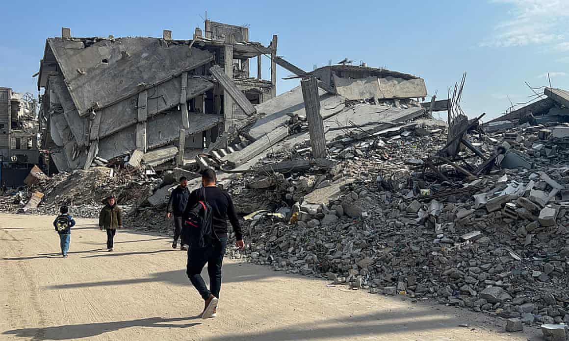 Palestinians walk past the rubble of destroyed houses