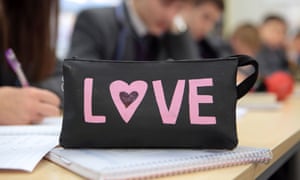 Children in a classroom behind a pencil case with LOVE on the side