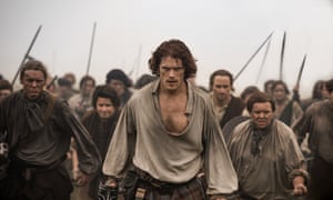 Sam Heughan and some extras carrying swords