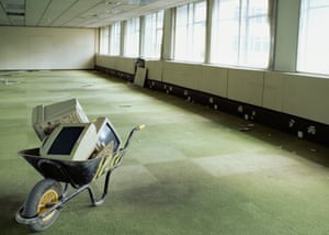 Wheelbarrow and computer monitors in empty office