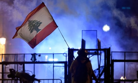 An anti-government protester waves a Lebanese flag during clashes with police outside parliament.