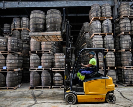 A worker uses a forklift to organise rum barrels