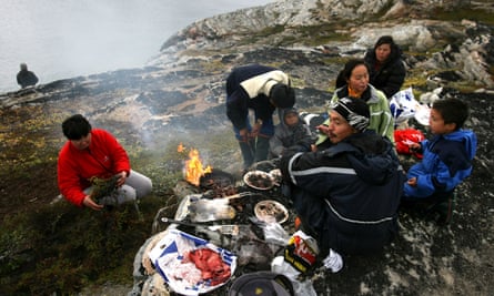 An Inuit fisherman and his family have a seal meat barbeque.