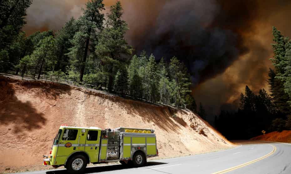 A fire engine drives past columns of dark smoke at the Dixie fire, a wildfire near the town of Greenville, California, in August.
