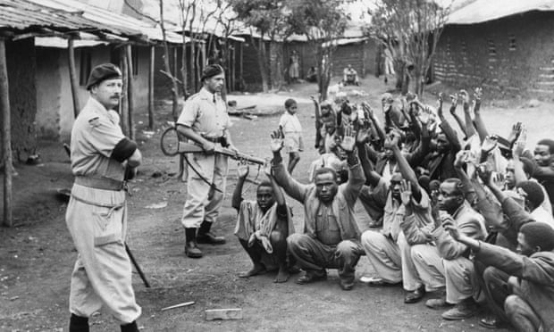 British police guarding suspected villagers while their huts are searched for evidence  they participated in the Mau Mau Rebellion of 1952