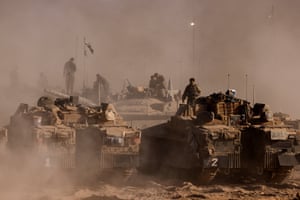 Soldiers stand on top of their vehicles parked in a desert setting