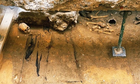 The excavated site reveals a human skull and bones. 