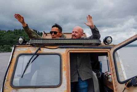 Two men on a boat wave through the cabin top.