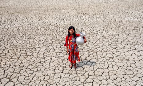 A girl walks through a cracked field after collecting drinking water from a pond in Satkhira, Bangladesh, March 2022.