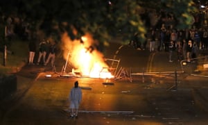 A masked man in front of a burning barricade on Fahan Street in Derry