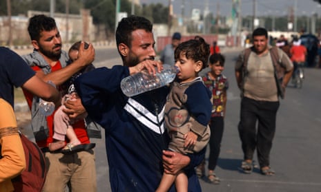 Men help toddlers to drink some water upon reaching the central Gaza Strip on foot via the Salah al-Din road on their way to the southern part of the Palestinian enclave on 5 November 2023.