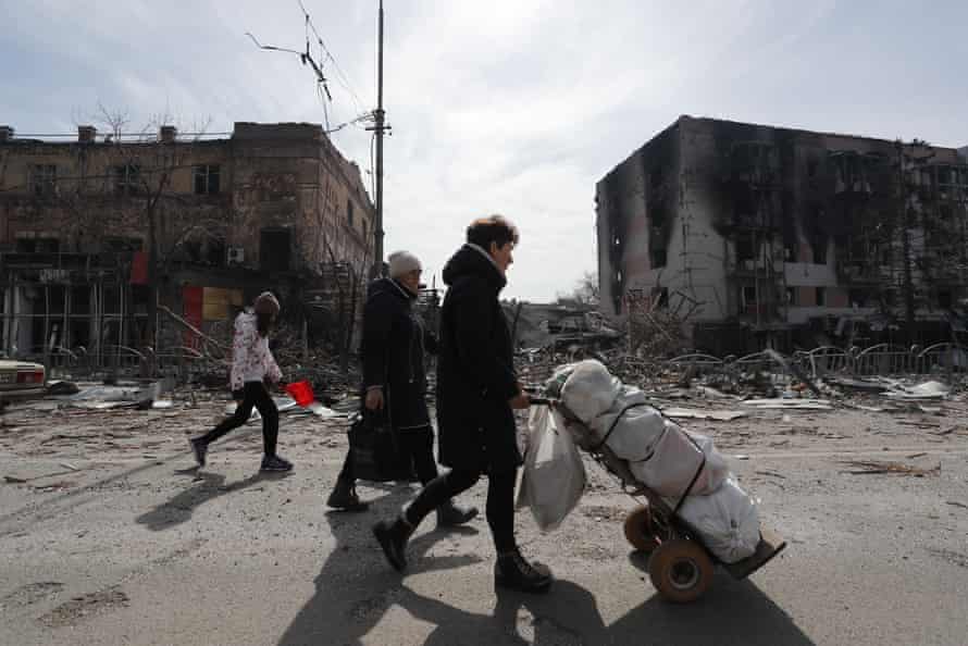 More than 10,000 civilians have died in the Ukrainian port city of Mariupol, the city’s mayor has said. Residents walk near damaged buildings in Mariupol.