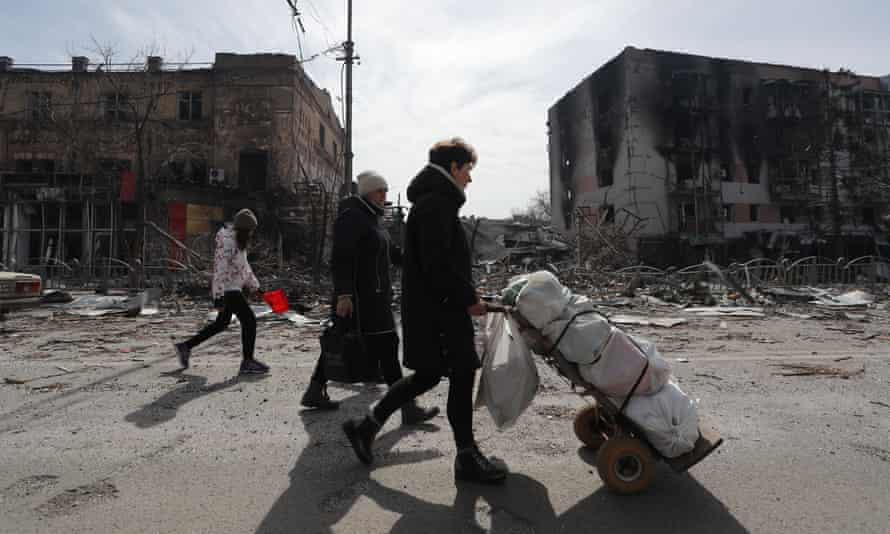 Moradores caminham perto de prédios danificados em Mariupol no domingo, 10 de abril.