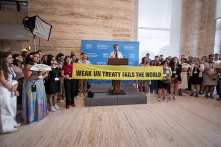 People stand with a banner that reads ‘Weak UN treaty fails the world’