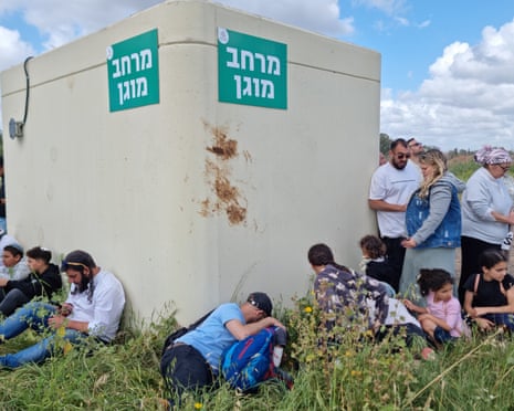 मध्य इज़राइल के होद हशारोन में ईरानी मिसाइल हमलों के दौरान सायरन बजते ही इज़राइली एक सार्वजनिक पार्क में बम आश्रय के चारों ओर छिप गए