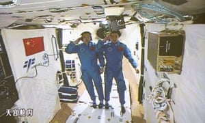 Chinese astronauts Jing Haipeng, left and Chen Dong salute in the space lab Tiangong 2.