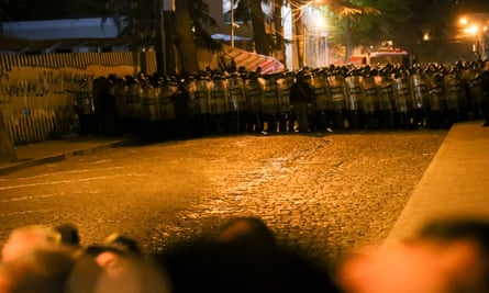 A line of police in riot gear block a street