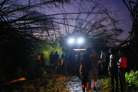 Workers clear downed trees and debris to make way for a convoy carrying aid to Black River, as it moves through Holland Bamboo, Jamaica.