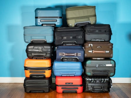 A pile of suitcases stacked up in front of blue wall