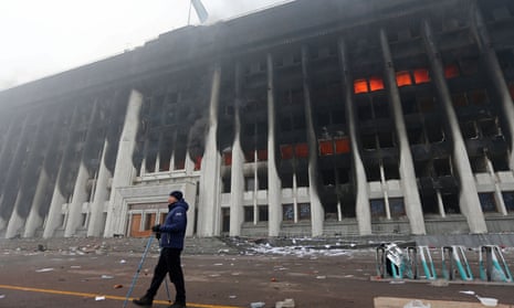 A man stands in front of the mayor's office building which was torched during protests triggered by fuel price increase in Almaty, Kazakhstan.