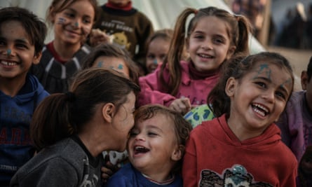 Children with blue face paint smile at the camera