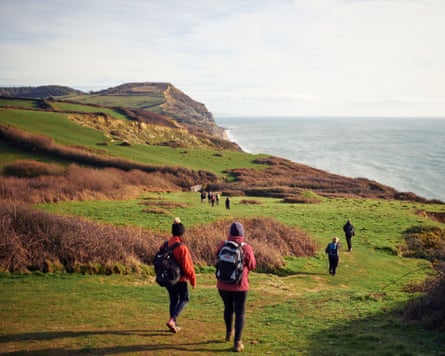People walking along a grassy coastal path