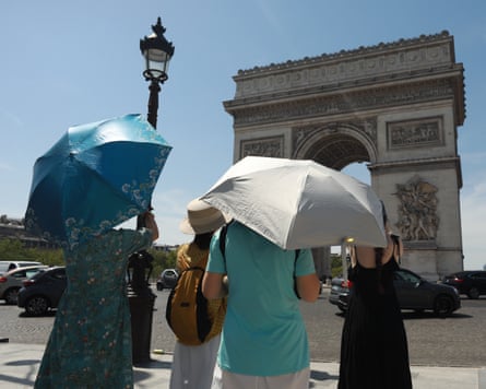 People shield from the sun using umbrellas near the Arc de Triomphe in Paris.