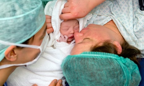 new born baby with mother and another person, seen close up