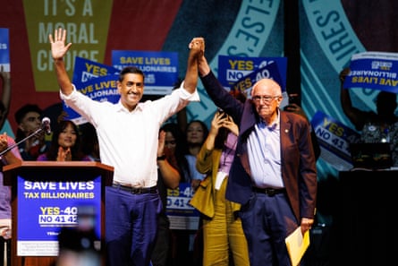 Ro Khanna and Bernie Sanders are raising their hands at an event.