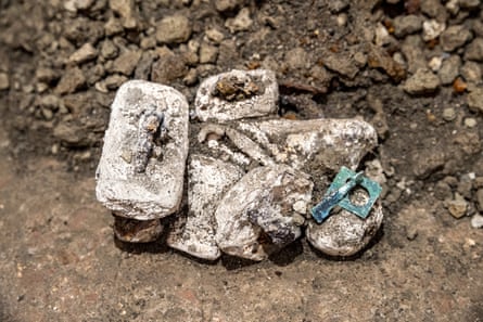 Corroded bronze weights and a box clasp set amid rocky soil