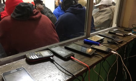 Phones charge while Haitians eat at a Tijuana migrant shelter.