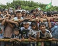 Crowds of Rohingya people gather behind a wooden fence.