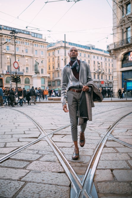A stylish man walking over tram tracks