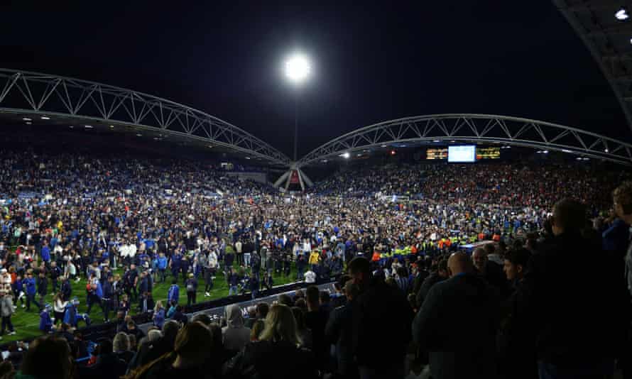 Huddersfield Town fans are on the field at the end of the game.