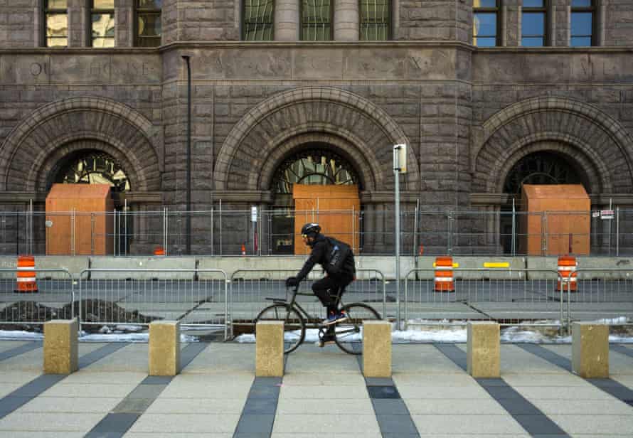 Boards stand in front of the windows and doors of Minneapolis city hall as barbed wire covered fencing are installed on the sidewalk before the jury selection begins in the trial of police officer Derek Chauvin on Monday.